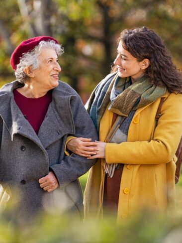 Senior woman walking with granddaughter in park during autumn